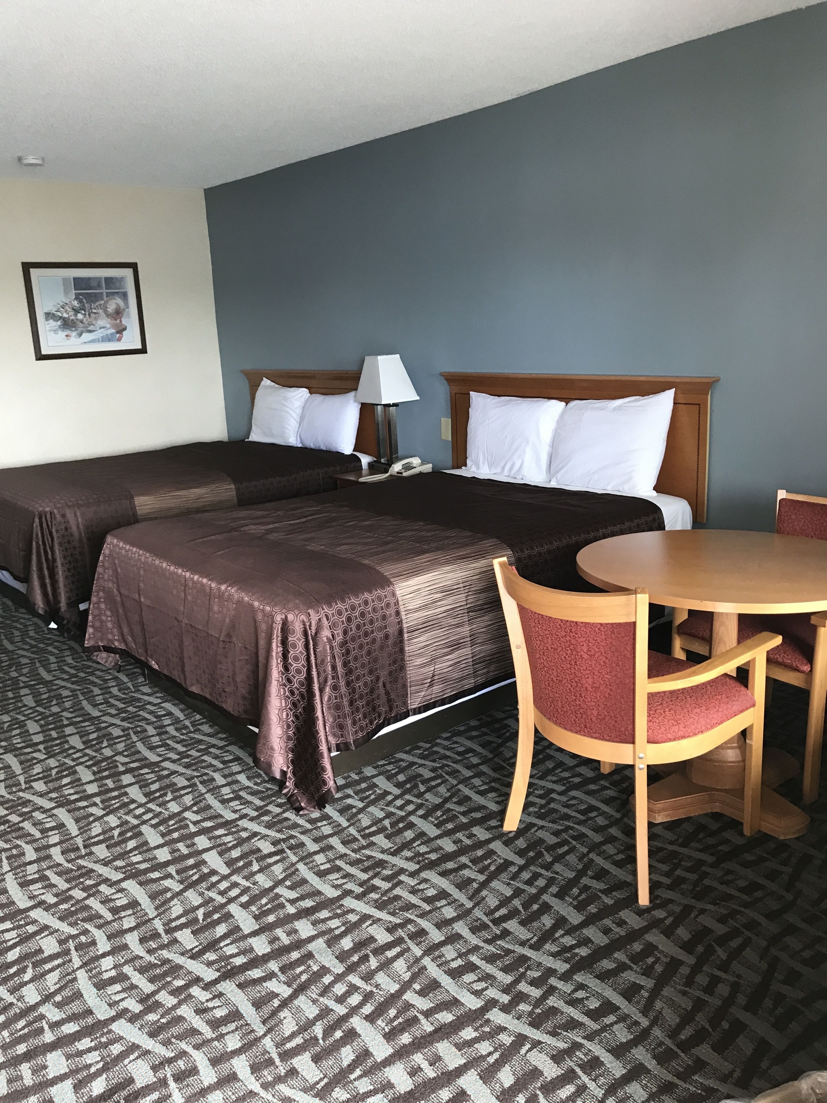 A hotel room with two beds, a dining table, and a chair.