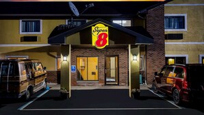 Un hôtel Super 8 avec une façade jaune, une enseigne « Super 8 » bien visible et un parking où sont garés deux fourgons.