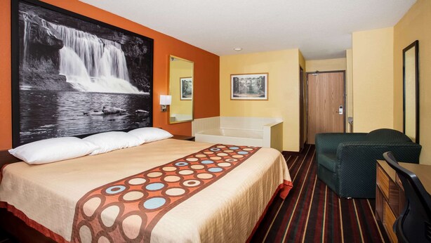 Une chambre d’hôtel comprenant un lit, un bureau, une chaise, une salle de bain et un grand tableau mural.