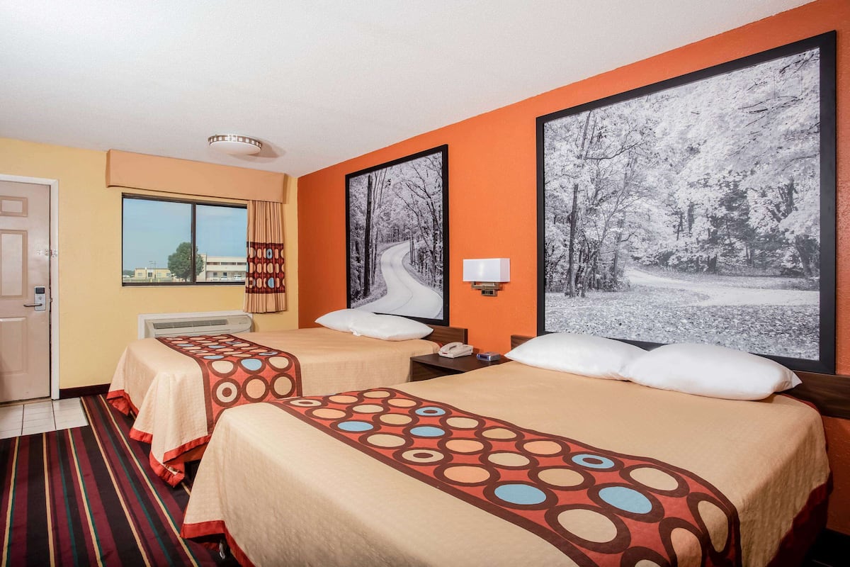 Ein Hotelzimmer mit zwei Betten, einem großen Fenster und Blick ins Freie.