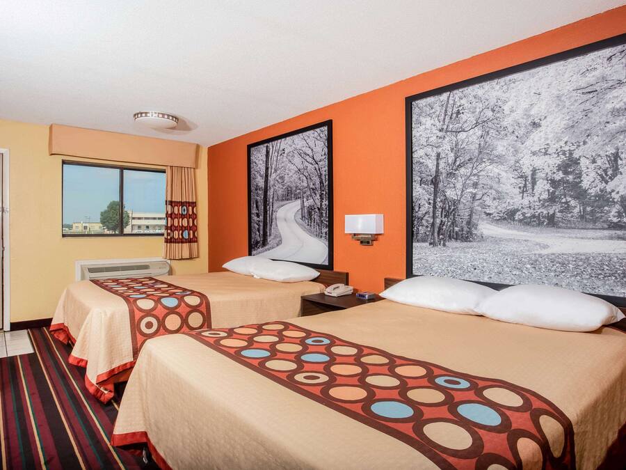 A hotel room with two beds, a large window, and a view of the outside.