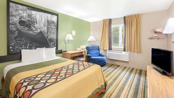 Ein Hotelzimmer mit Bett, Schreibtisch, Stuhl, Fernseher und einem Fenster mit Vorhängen.