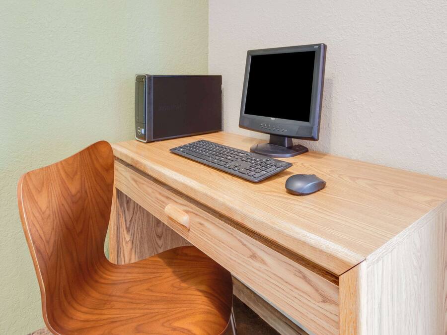 Un escritorio de madera con un equipo informático que incluye un monitor, teclado y ratón.