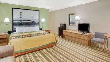 Una habitación de hotel con cama, escritorio con televisor, silla y lámpara.