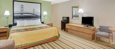Una habitación de hotel con cama, escritorio con televisor, silla y lámpara.