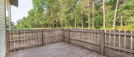 A wooden deck with a wooden fence, surrounded by trees.