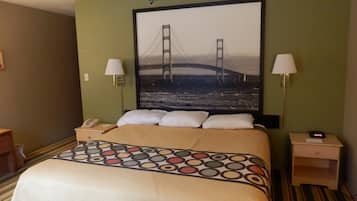 Una habitación de hotel con una cama, dos lámparas de noche, una mesita de noche con un teléfono y un cuadro de un puente en la pared.