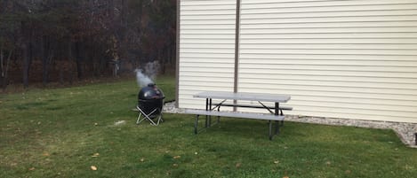 Un patio trasero con una parrilla de barbacoa y una mesa de picnic.