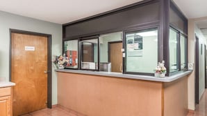 A reception area with a counter, a utility room door, and a bulletin board with posted notices.