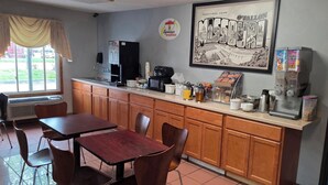 A diner-style restaurant with a counter, chairs, a coffee machine, and a wall poster.