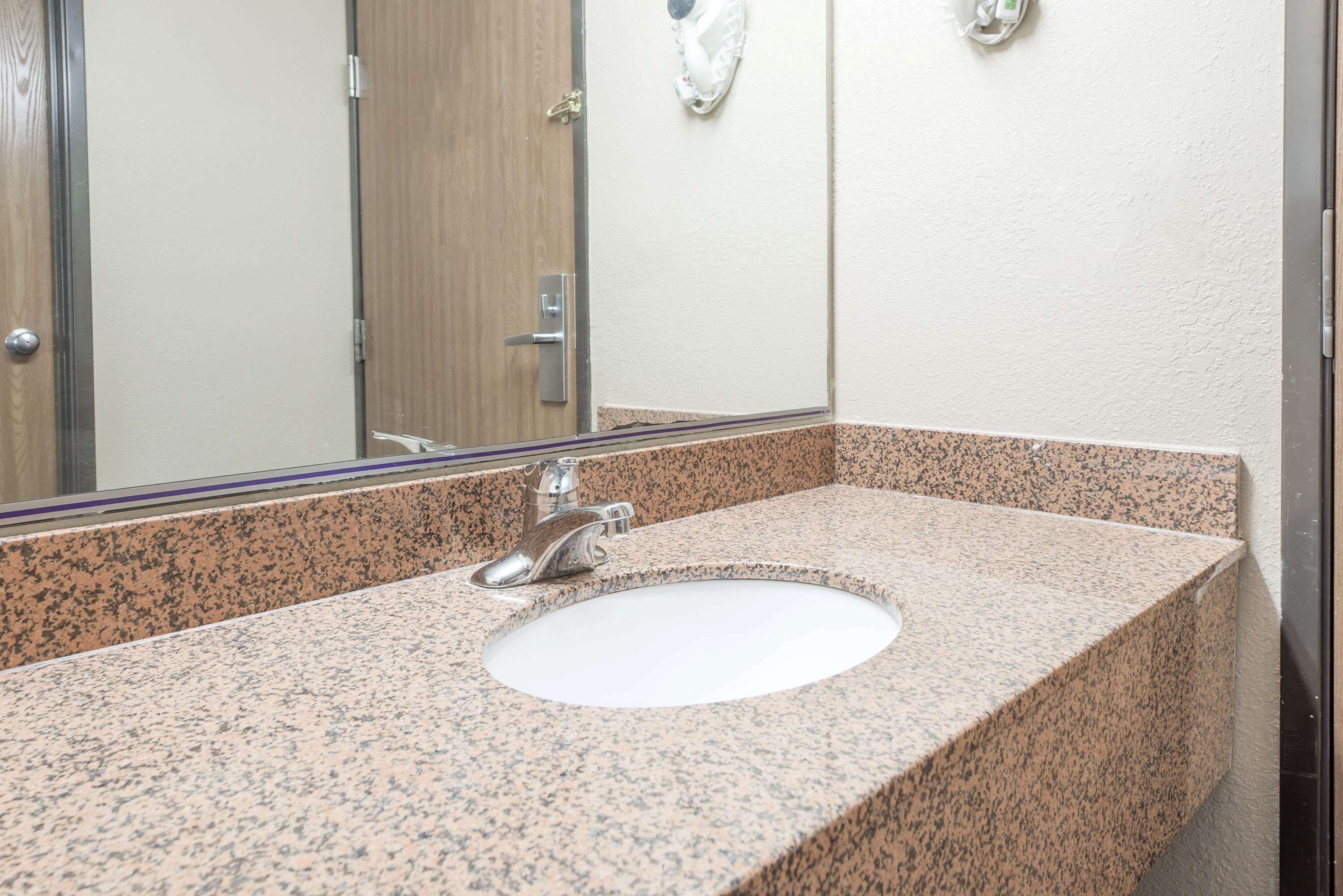 A bathroom with a granite countertop, a white sink, and a mirror.
