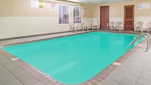 A swimming pool with a tiled deck, safety chairs, and a lifeguard sign.
