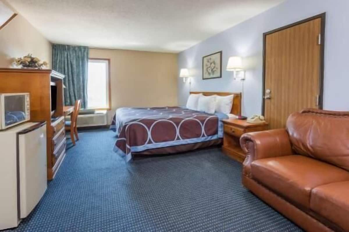 Une chambre d’hôtel comprenant un lit, un bureau, une chaise, un canapé en cuir et un téléviseur.