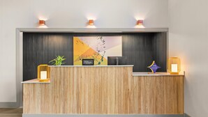Un comptoir d’accueil d’hôtel avec un revêtement en bois, un grand logo Hilton Honors et deux appliques murales.