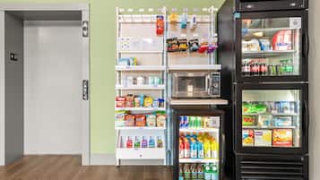 Una macchina distributrice con snack e bevande, un frigorifero con bibite e un forno a microonde.
