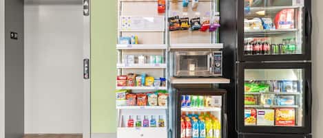 Un distributeur automatique de collations et de boissons, un réfrigérateur rempli de boissons et un four à micro-ondes.