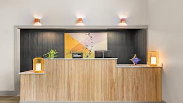 Un mostrador de recepción de hotel con detalles de madera, un gran logotipo de Hilton Honors y dos lámparas fijadas a la pared.