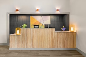 Un mostrador de recepción de hotel con detalles de madera, un gran logotipo de Hilton Honors y dos lámparas fijadas a la pared.