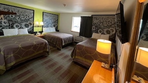 A hotel room with two beds, a desk, a TV, and a window with curtains.