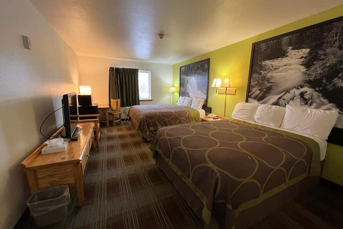A hotel room with two beds, a desk with a computer, and a TV.