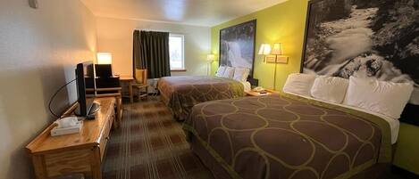 A hotel room with two beds, a desk with a computer, and a TV.