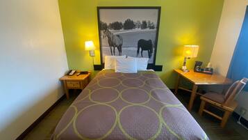 Habitación de hotel con cama, dos mesitas de noche, escritorio, silla y lámpara de pared.