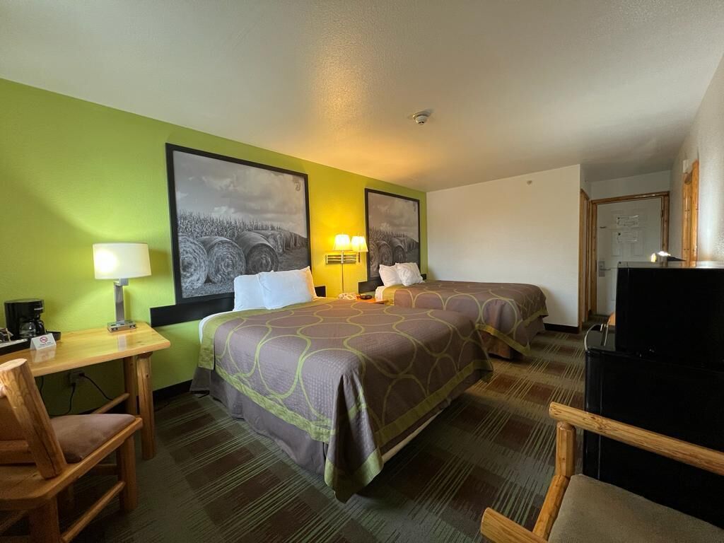 Une chambre d’hôtel avec deux lits, un bureau avec une lampe, une chaise et un téléviseur.