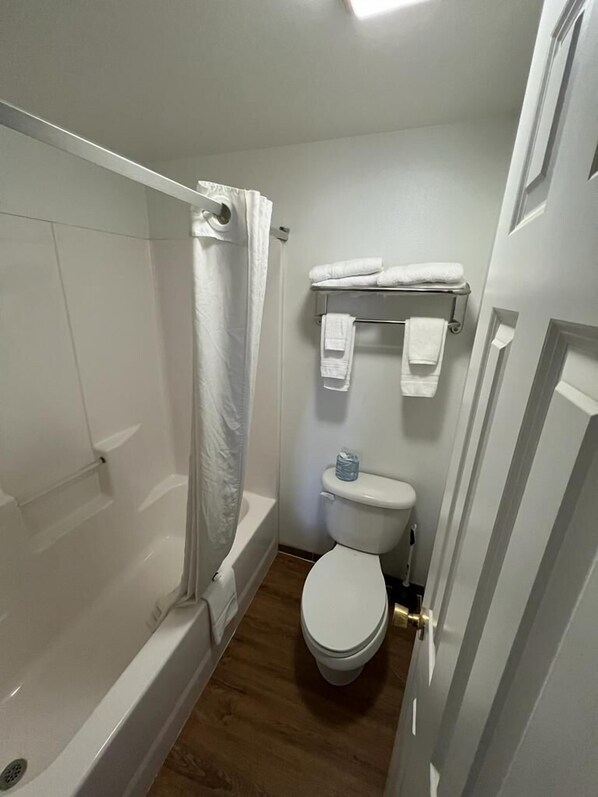 A small, clean bathroom with a bathtub, toilet, and towel rack.
