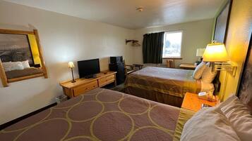 Habitación de hotel con dos camas, un escritorio con lámpara, televisión y ventana con cortinas.