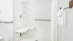 A modern bathroom with a shower, grab bar, and a towel rack.