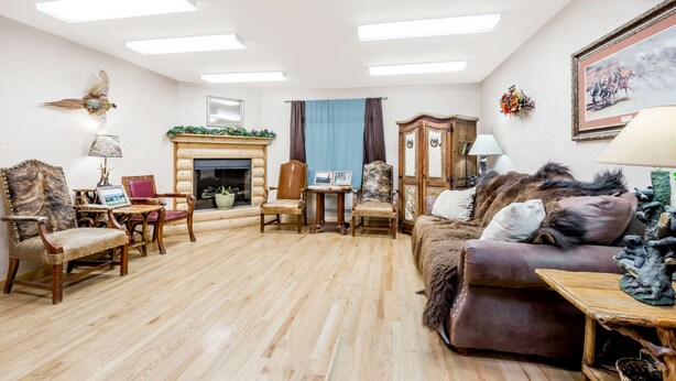 A spacious living room with a fireplace, wooden furniture, and a large window.