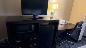 Une chambre d’hôtel équipée d’un téléviseur à écran plat, d’un mini-réfrigérateur, d’un four à micro-ondes, d’un bureau avec une lampe et d’une chaise.