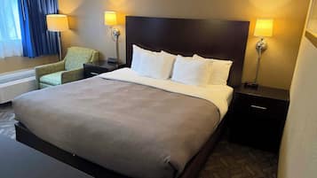 Una habitación de hotel con una cama grande, dos mesitas de noche, una silla y un escritorio.