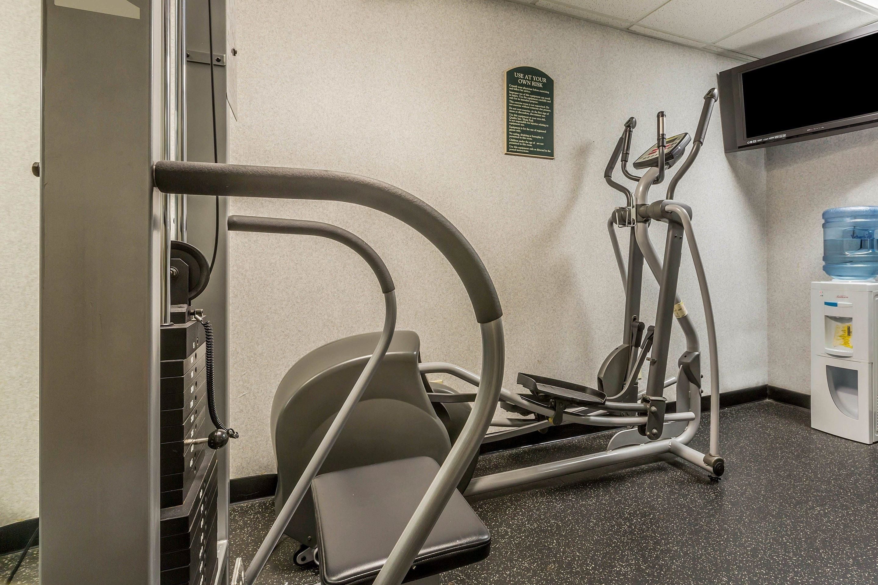 A fitness area with exercise equipment, a water dispenser, and a television on the wall.
