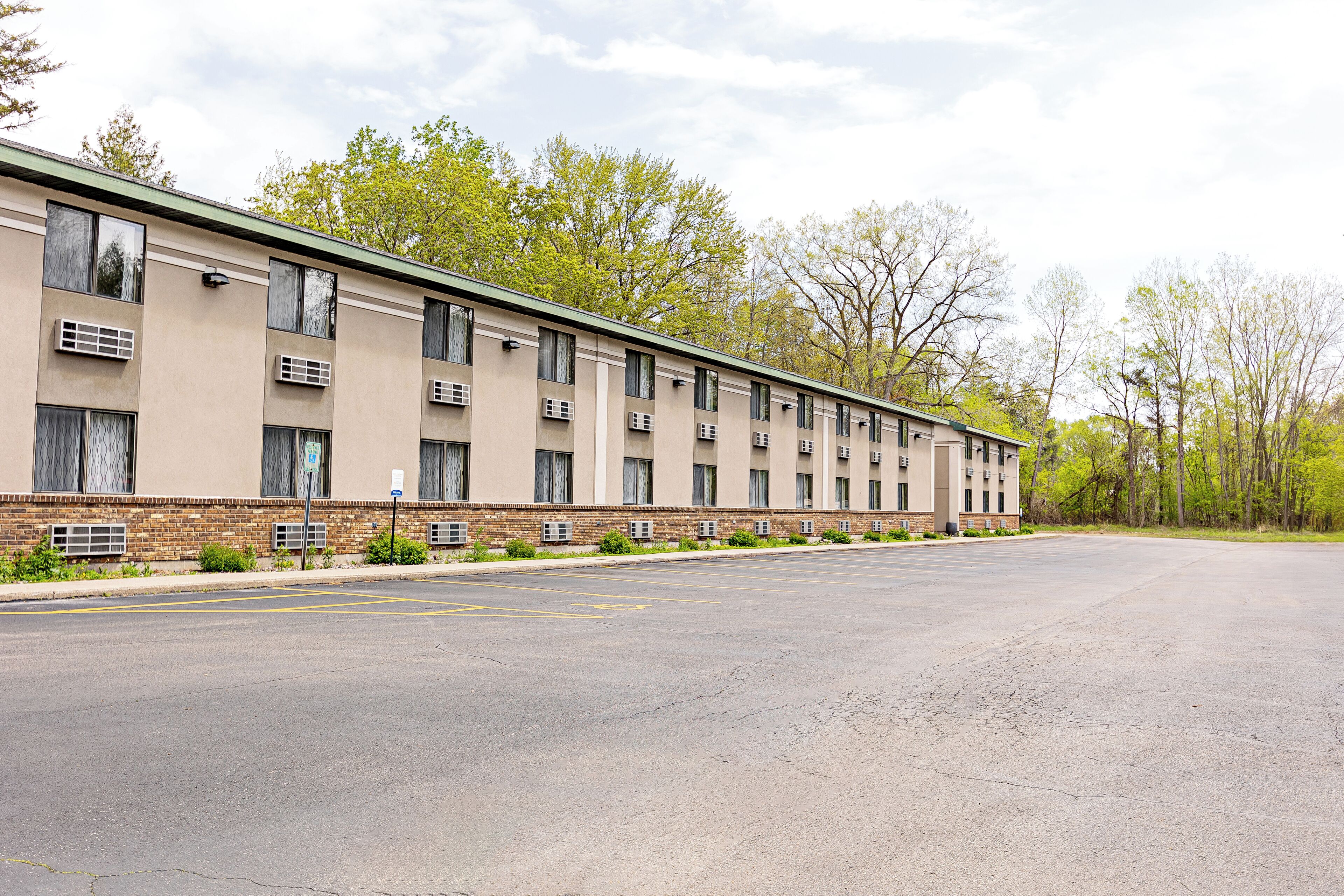 A multi-story hotel with a flat roof, air conditioning units, and a parking lot.