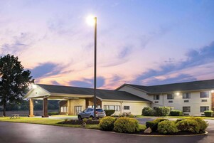 Um motel com área de estacionamento coberta, mesa para piquenique e um carro estacionado na frente.