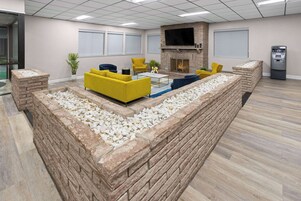 Uma área de estar moderna com sofás amarelos, uma lareira de pedra e uma televisão de tela plana.
