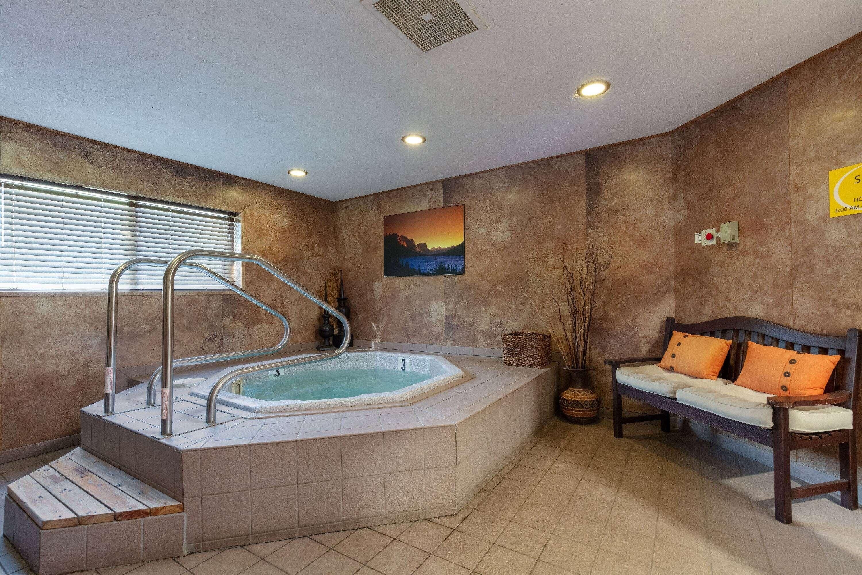 A spa area with a hot tub, a wooden bench, and a painting on the wall.