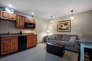 A compact living space with a kitchenette, a sofa, and a coffee table. - Super 8 by Wyndham St. Regis (St. Regis)