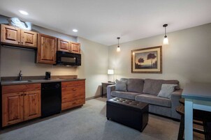 Un espacio habitable compacto con kitchenette, un sofá y una mesa de centro.