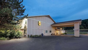 A large building with a prominent '8' sign, a covered parking area, and a well-maintained exterior. - Super 8 by Wyndham St. Regis (St. Regis)