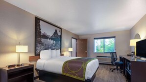 Una habitación de hotel con cama, escritorio, silla y un ventanal grande.