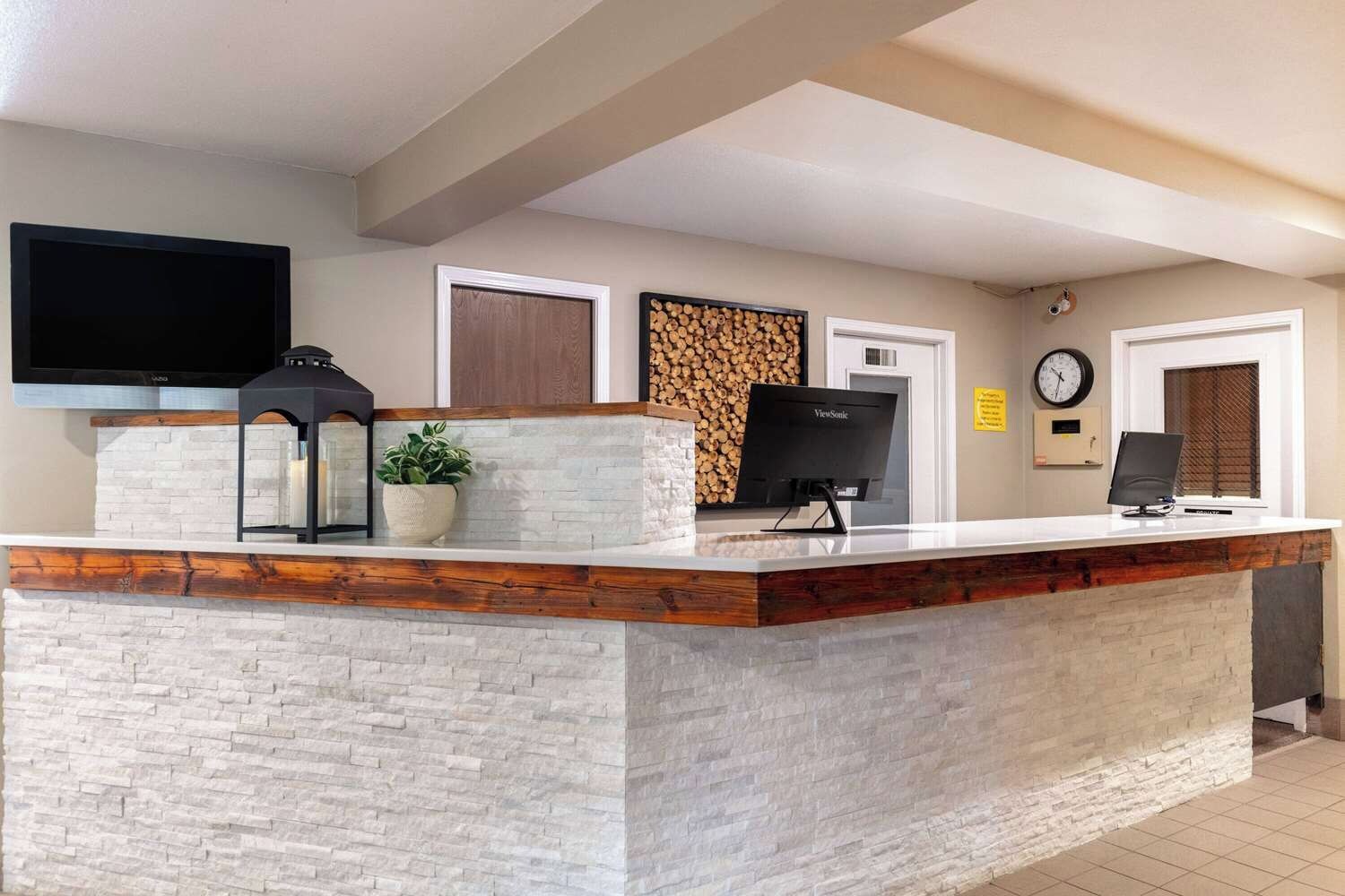 A reception desk with a stone facade, a flat-screen TV, a clock, and a firewood display.