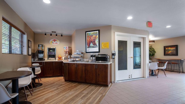 A modern kitchen with a wooden countertop, white chairs, and a dining area with a table and chairs. - Super 8 by Wyndham St. Regis (St. Regis)