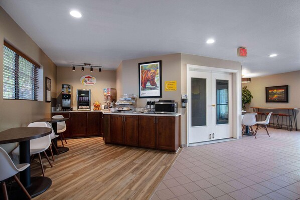 A modern kitchen with a wooden countertop, white chairs, and a dining area with a table and chairs. - Super 8 by Wyndham St. Regis (St. Regis)
