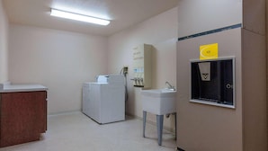 A small, clean bathroom with a washing machine, a sink, and a mirror. - Super 8 by Wyndham St. Regis (St. Regis)