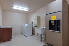 A small, clean bathroom with a washing machine, a sink, and a mirror. - Super 8 by Wyndham St. Regis (St. Regis)