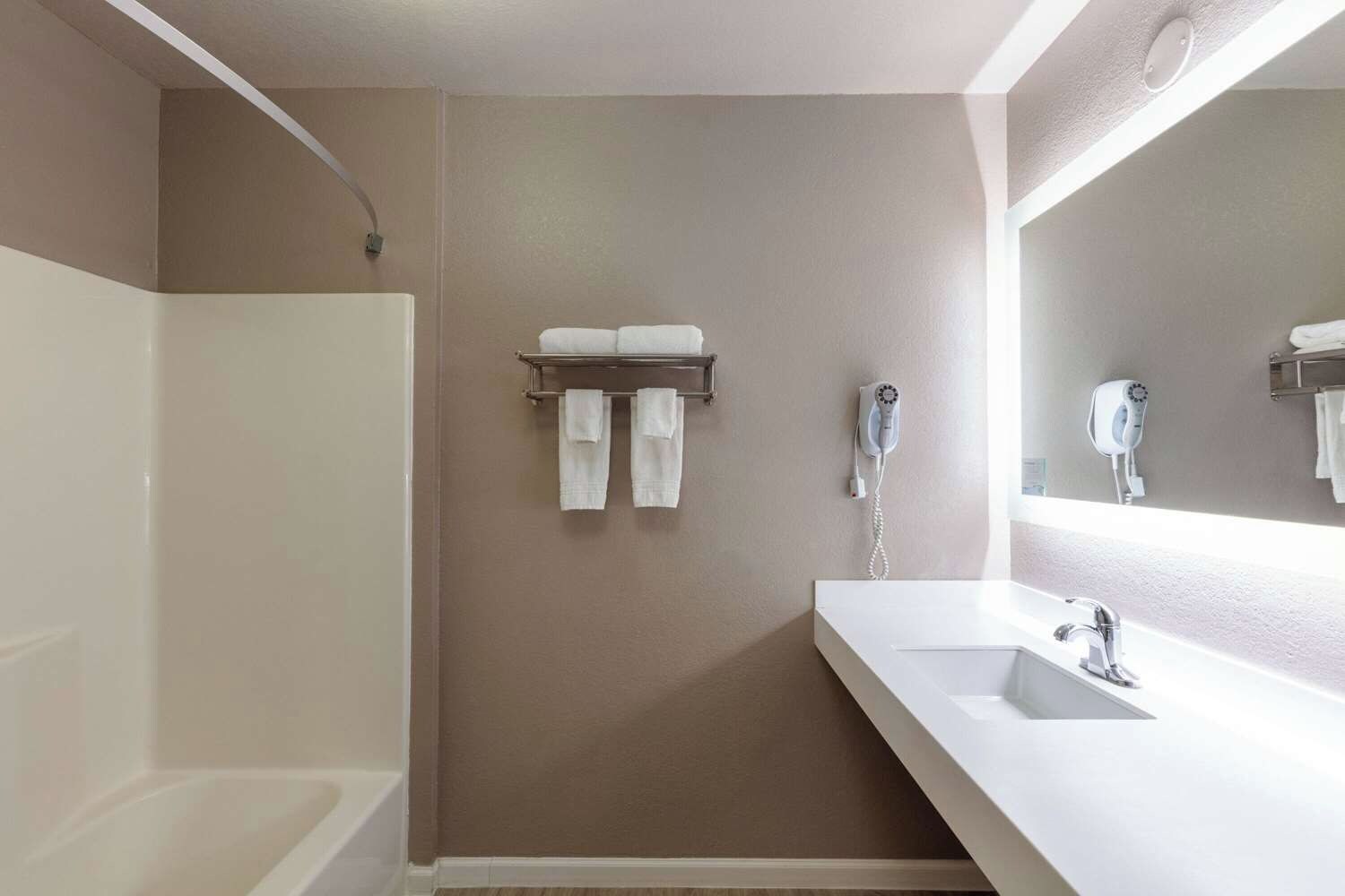 Un baño moderno con una bañera, un lavabo, un espejo y un perchero con dos toallas.