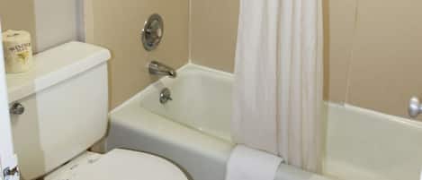 Un baño con inodoro, bañera y cortina de ducha.