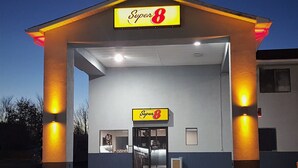 A Super 8 motel with a bright yellow sign, a well-lit entrance, and a visible front desk area. - Super 8 by Wyndham Locust Grove (Locust Grove)